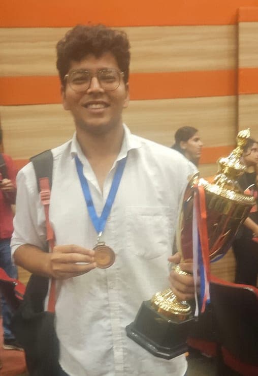 Portrait of Suraj Singh holding a trophy and medal